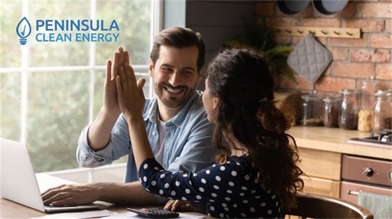 Photo of two people high fiving at a desk with a computer
