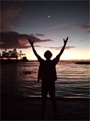 Person with hands up doing Qi Gong on the beach at sunset
